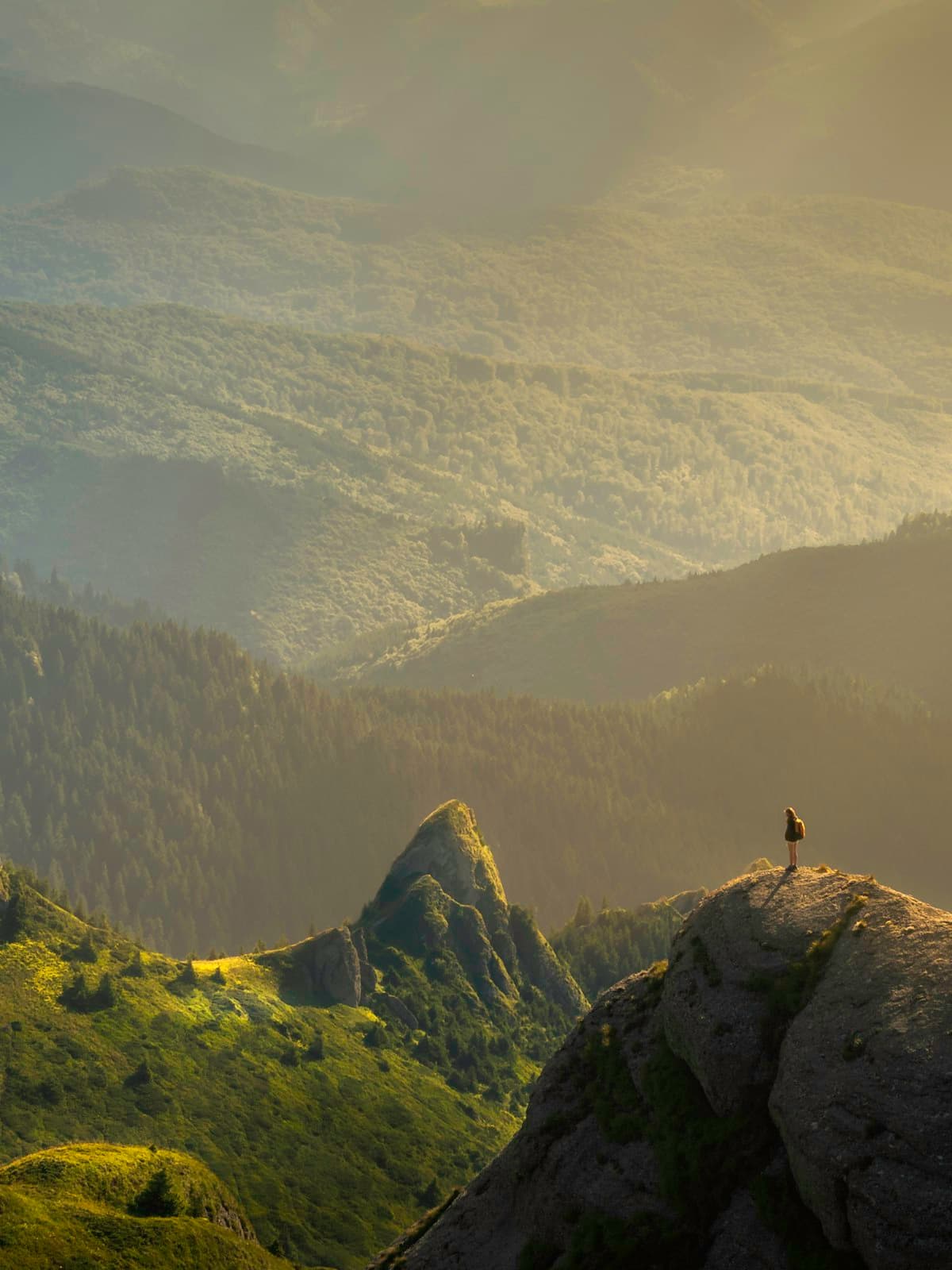 Solitary figure overlooking misty mountain ridges at golden hour